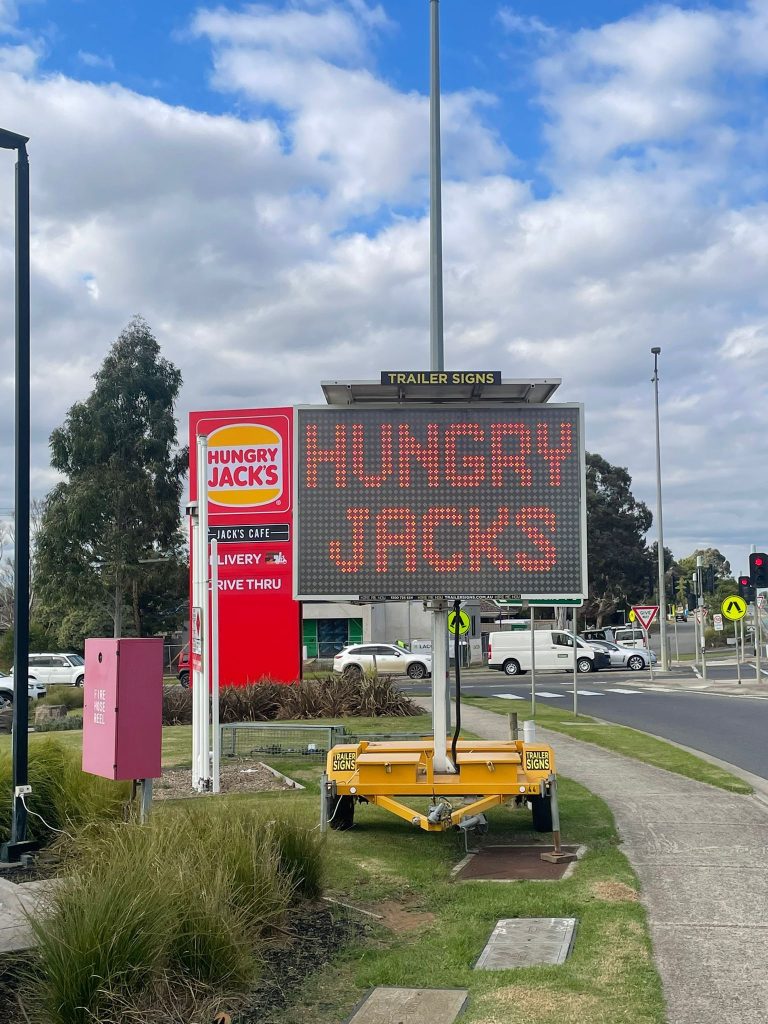 5-colour VMS trailer sign advertising "Hungry Jacks is open" outside Cranbourne West restaurant
