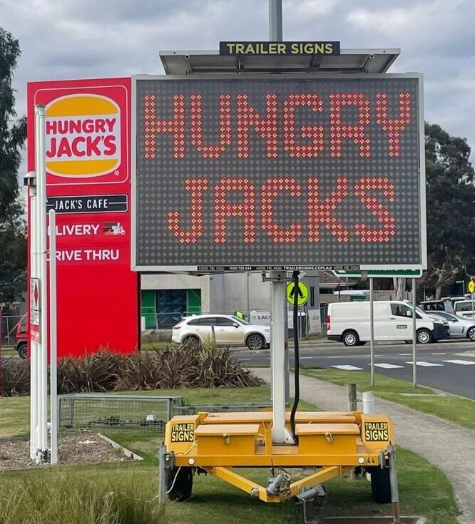 5-colour VMS trailer sign advertising "Hungry Jacks is open" outside Cranbourne West restaurant